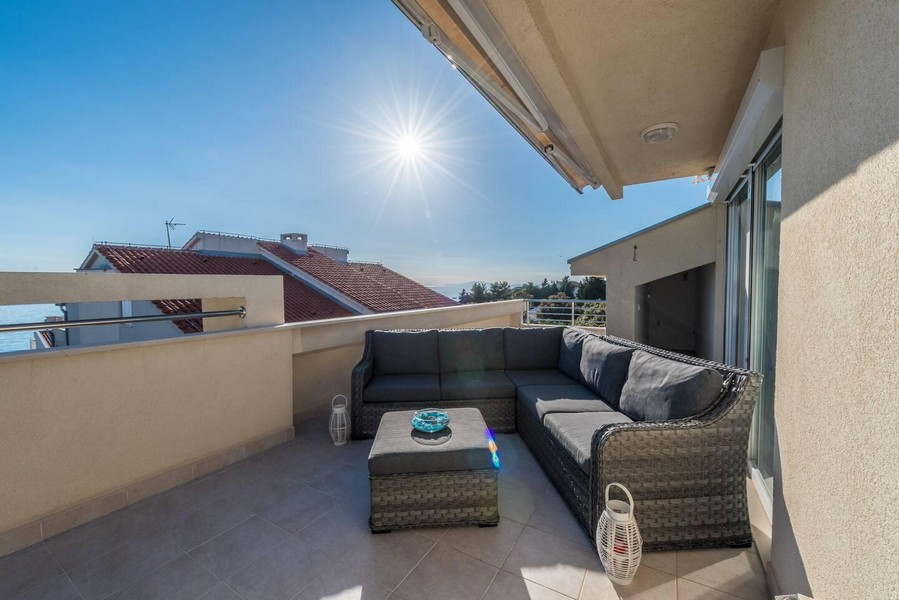 Slunná střešní terasa s posezením a výhledem na moře