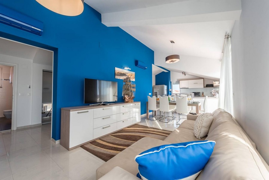 Obývací prostor s modrou stěnou a otevřenou kuchyní