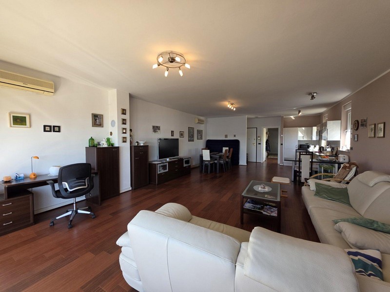 Světlý obývací pokoj s parketami, koženou pohovkou a výhledem na moře