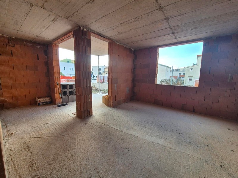 Skořápka bytu s odhalenými cihlovými zdmi a velkým oknem