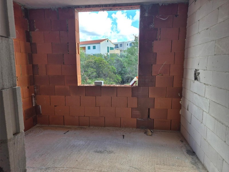 Nedokončený obytný prostor s výhledem na sousední domy velkým oknem