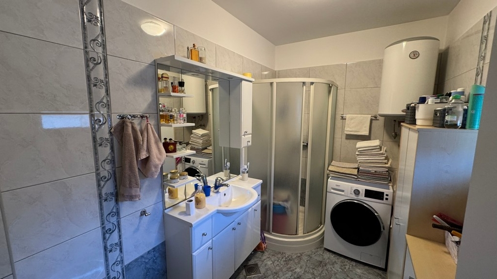 Koupelna se sprchovým koutem, pračkou a umyvadlem se zrcadlem