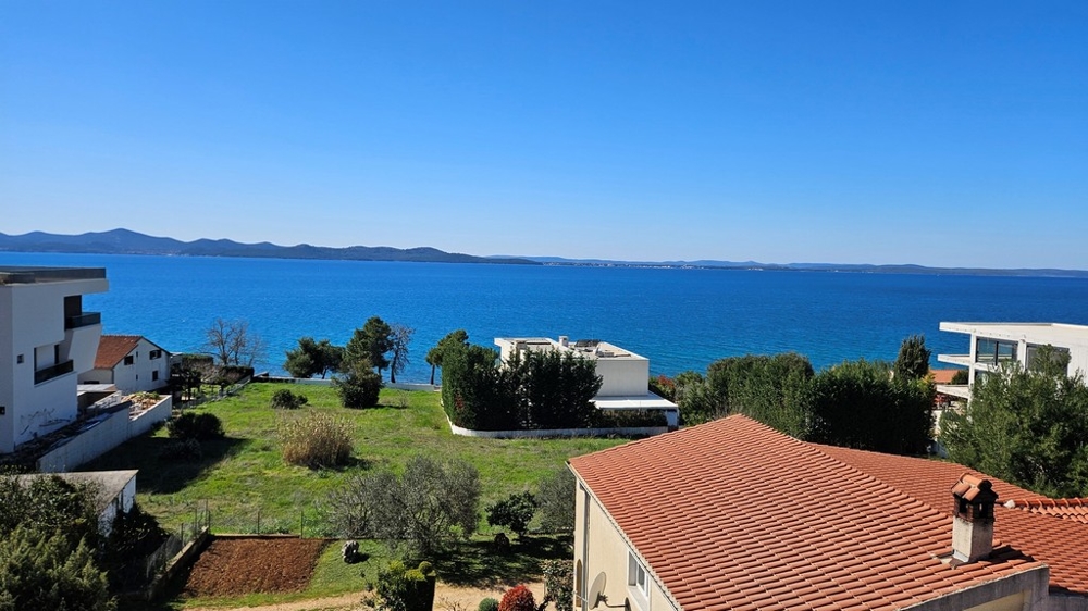 Střešní terasa s výhledem na bazén a moře při západu slunce