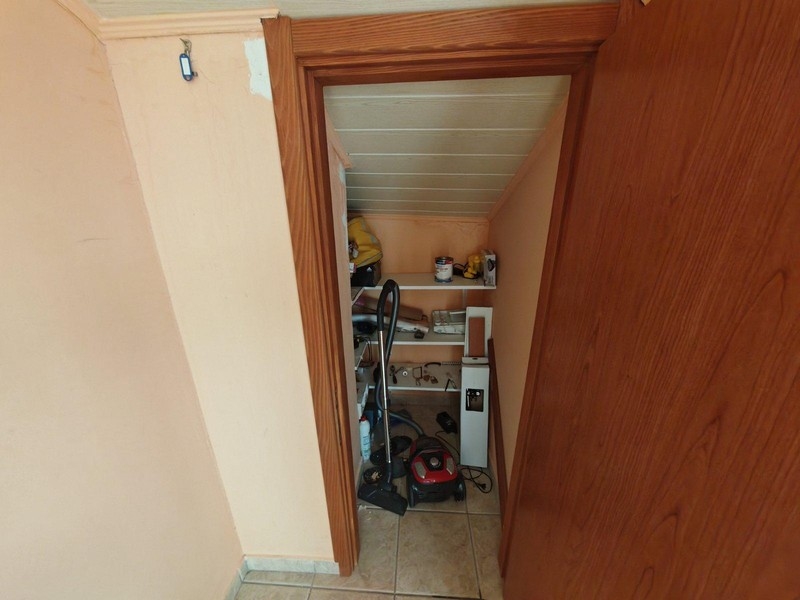 Malý úložný prostor s policemi a vysavačem