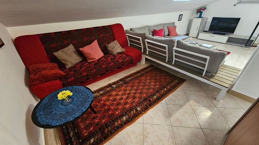 Obývací pokoj v podkroví se sedací soupravou a televizí