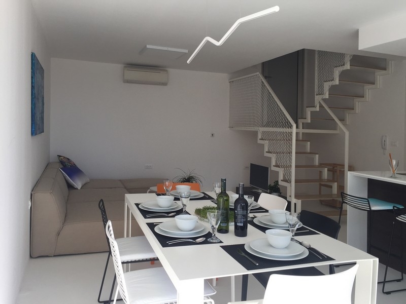 Obývací pokoj se sedací soupravou, jídelním koutem a schodištěm na galerii