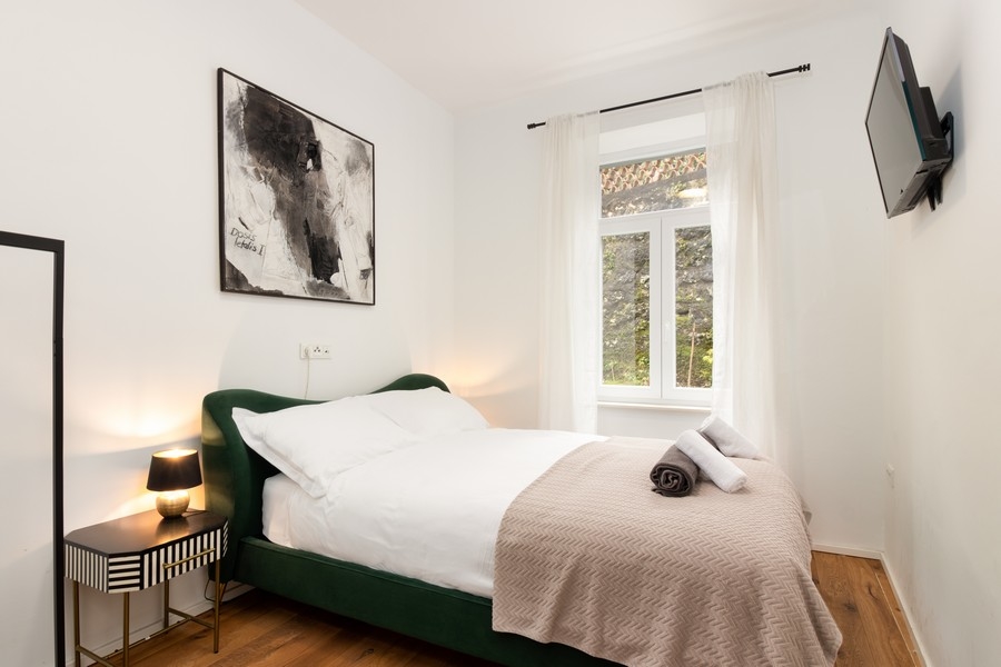 Ložnice se zelenou postelí a nočním stolkem