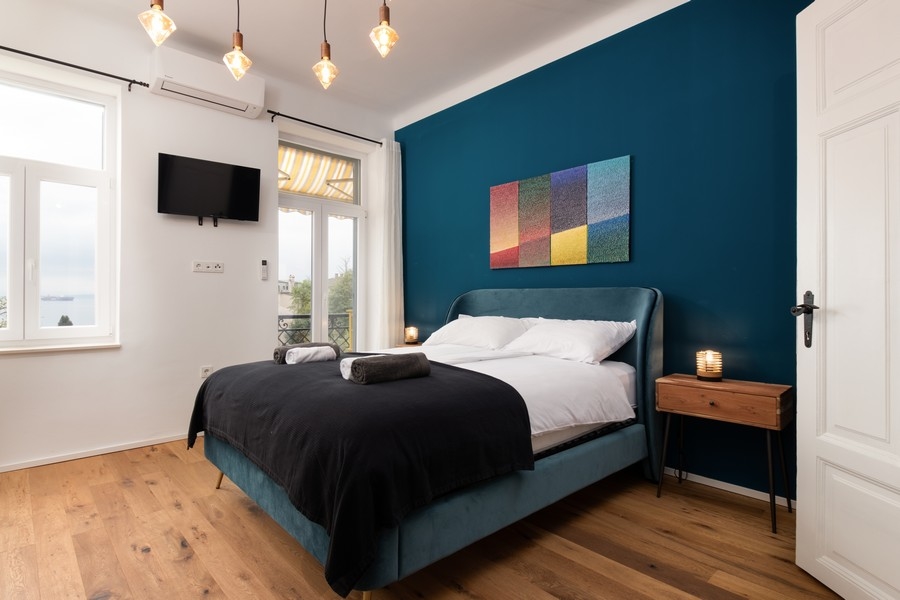 Ložnice s výhledem na moře a tmavě modrou stěnou