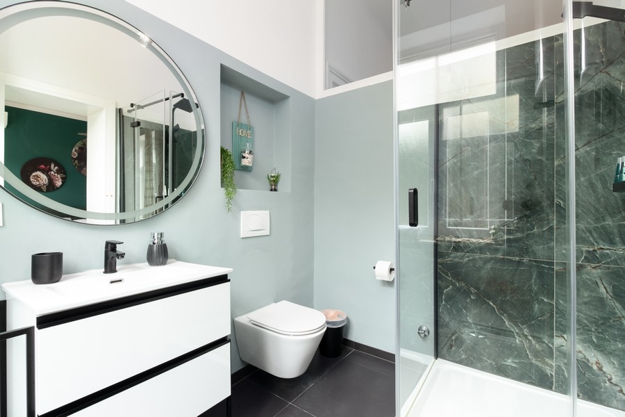 Koupelna s kulatým zrcadlem a skleněnou sprchou