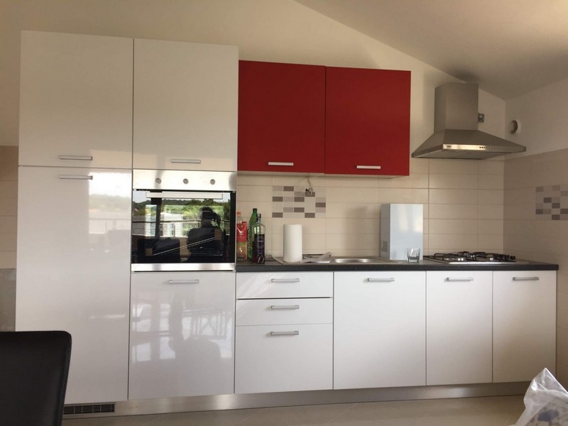 Zařízená kuchyně s červenými horními skříňkami
