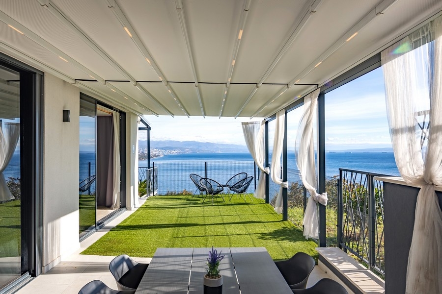 Krytá terasa se zahradou a panoramatickým výhledem na moře.