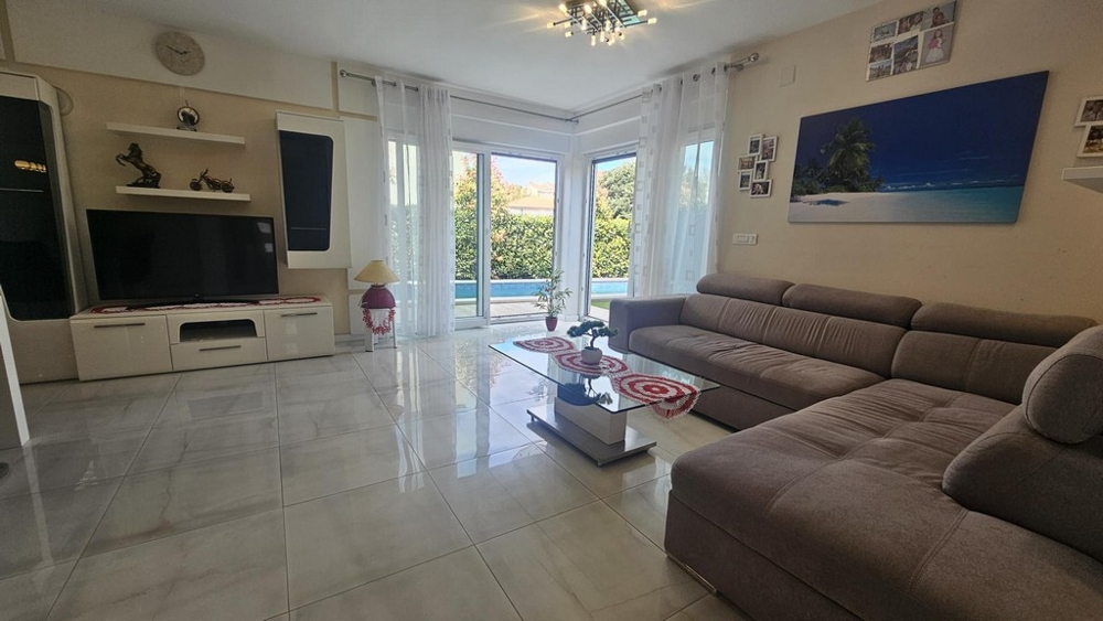 Světlý obývací pokoj s rohovou pohovkou a TV