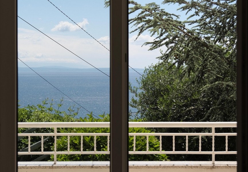 Výhled na moře z balkonu velkými prosklenými dveřmi