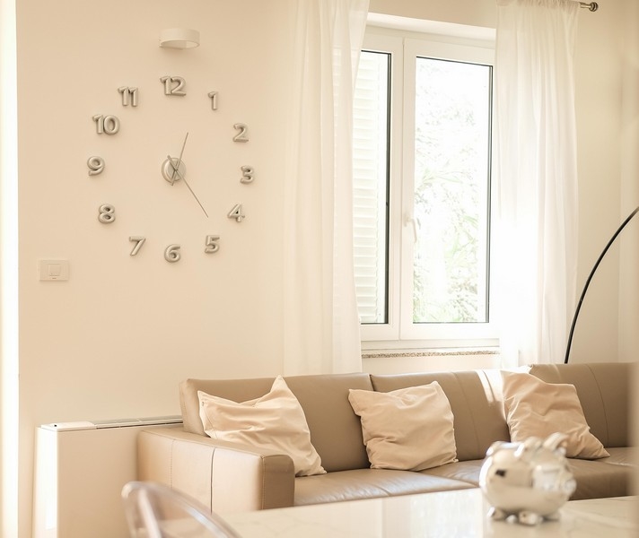 Obývací pokoj s nástěnnými hodinami a výhledem do zeleně