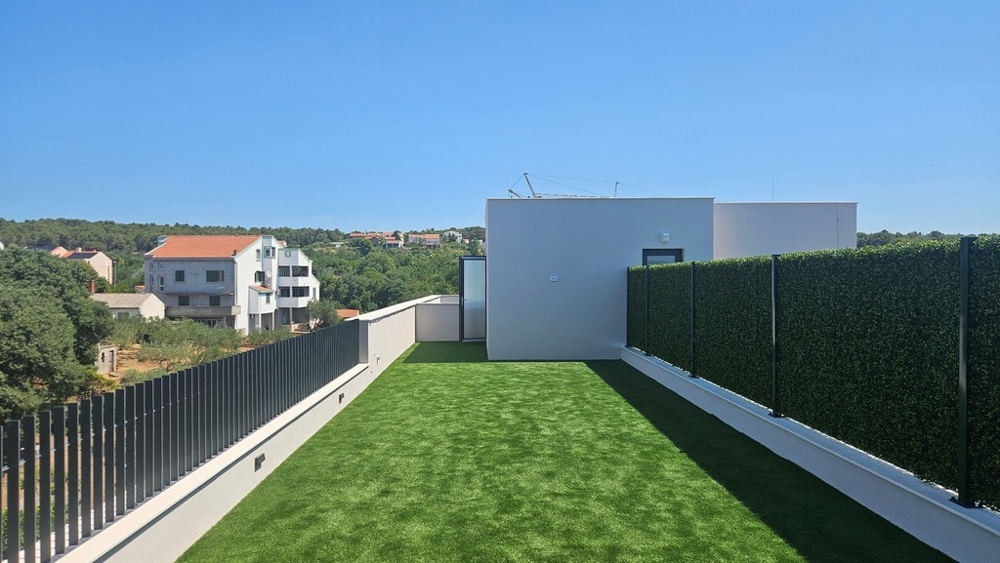 Střešní terasa s umělým trávníkem a výhledem do krajiny