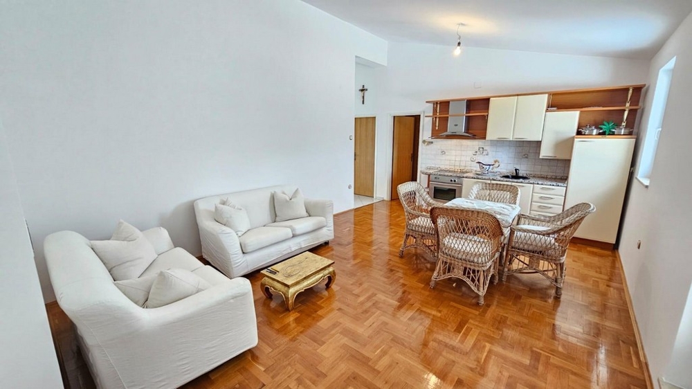 Obývací pokoj s pohovkou, ratanovými křesly a kuchyní