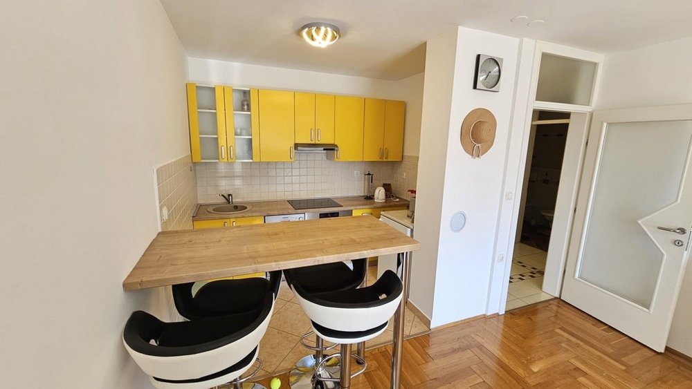 Kuchyň se žlutými vestavěnými skříněmi a barovým pultem