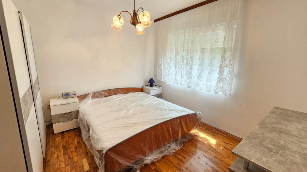 Ložnice s manželskou postelí, šatní skříní a oknem s denním světlem