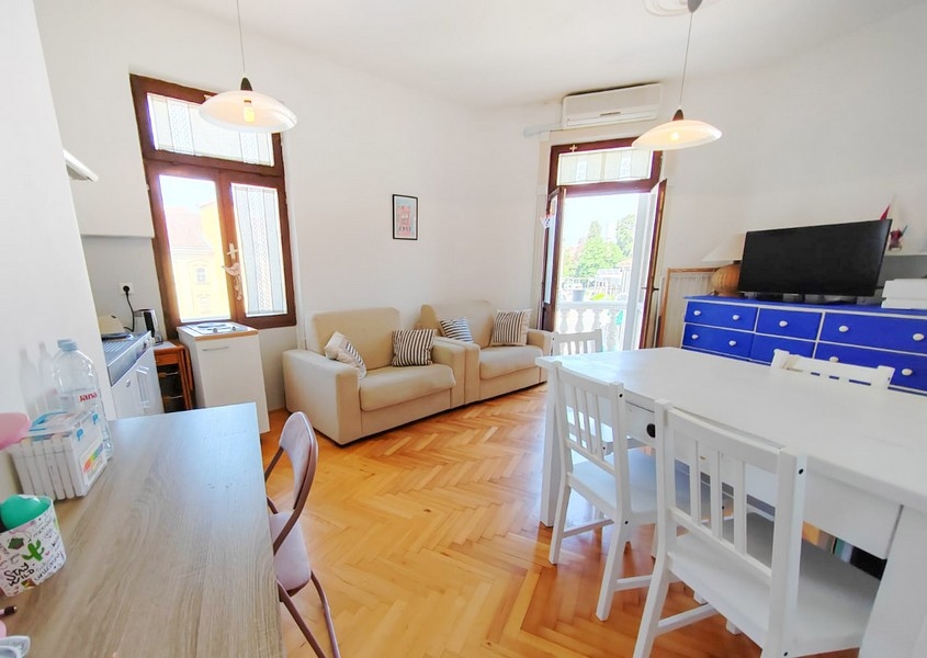 Světlý obývací pokoj s pohovkou a jídelním stolem