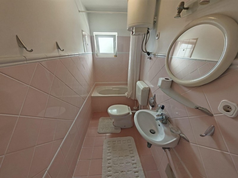 Koupelna s vanou a růžovými obklady