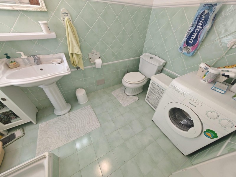 Koupelna s pračkou a zelenými obklady