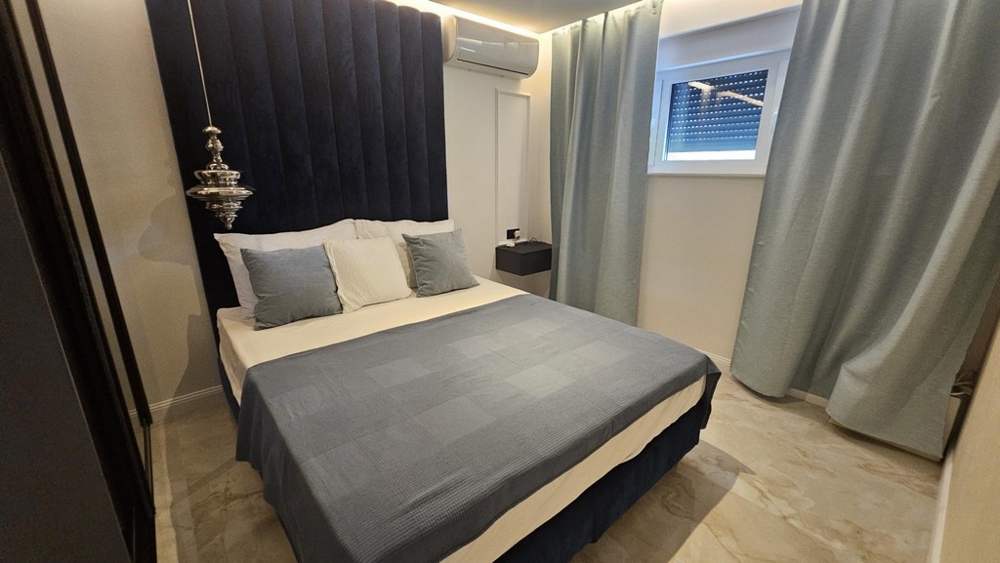 Ložnice s manželskou postelí a tmavě modrým čelem