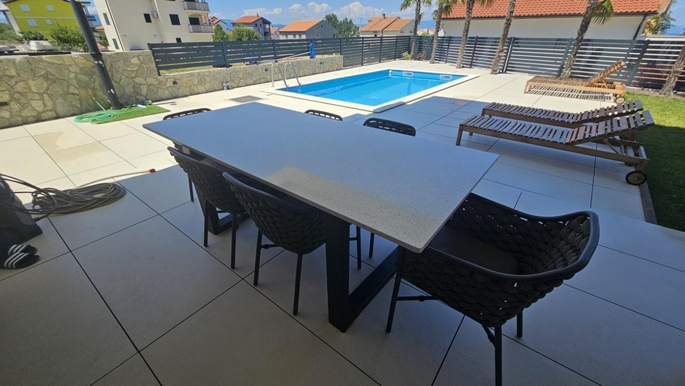 Terasa s jídelním stolem, výhledem na bazén a lehátky
