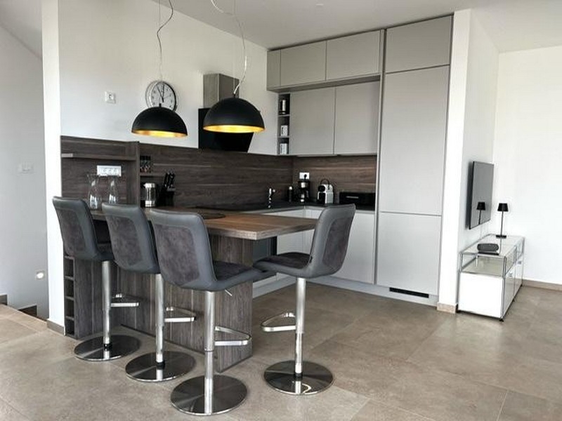 Moderně vybavená kuchyně s barovým pultem a stoličkami