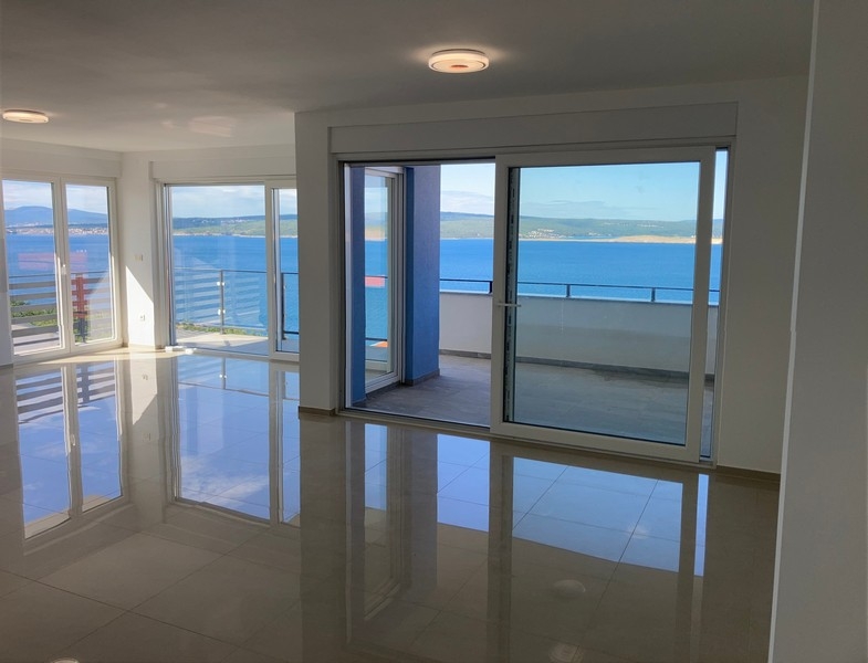 Obývací pokoj s velkými okny a výhledem na moře
