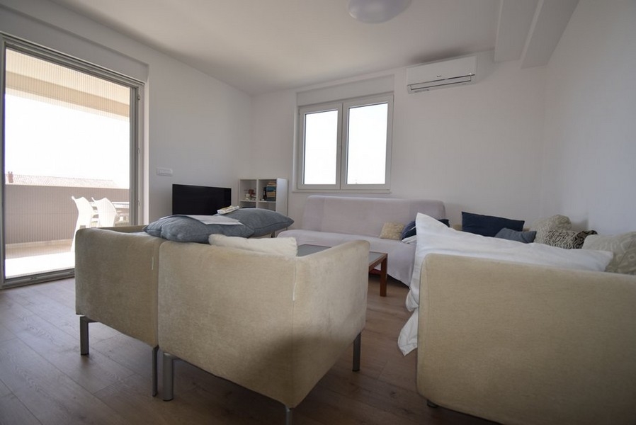 Světlý obývací pokoj se sedací soupravou a vstupem na terasu