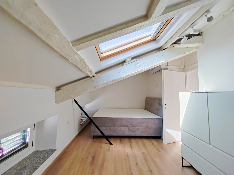 Druhá ložnice v podkroví s postelí a střešními trámy