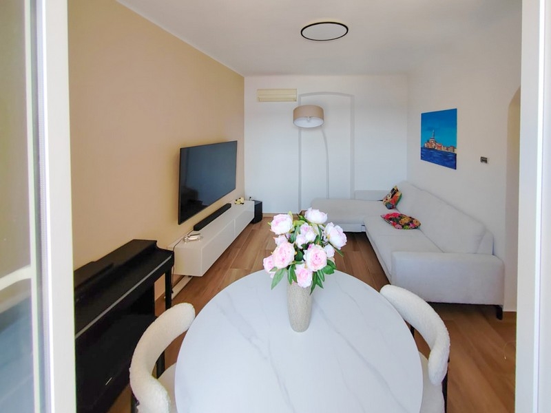 Světlý obývací pokoj s pohovkou a jídelním stolem