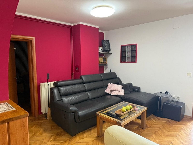 Obývací pokoj s černou koženou pohovkou a konferenčním stolkem