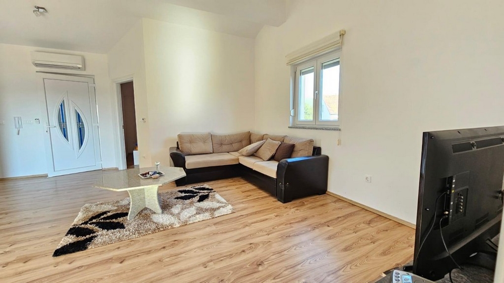 Světlý obývací pokoj s pohovkou a televizí