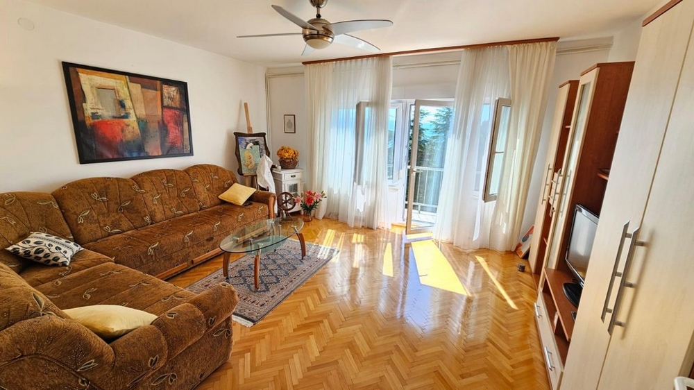 Světlý obývací pokoj s pohovkou a přístupem na balkon