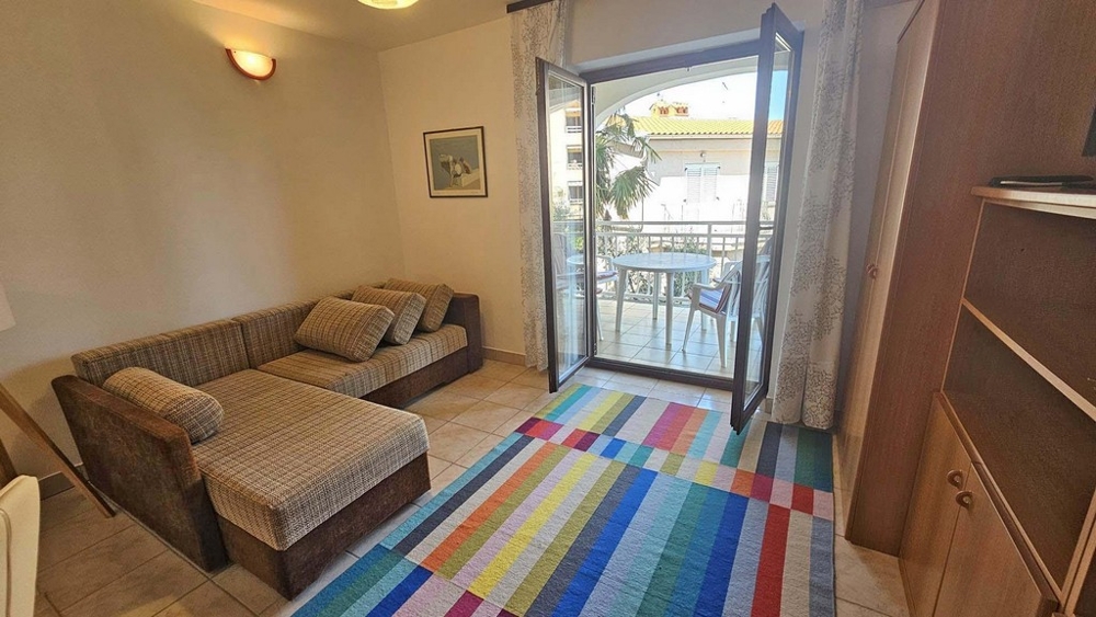 Obývací pokoj se sedací soupravou, kobercem a vstupem na balkon