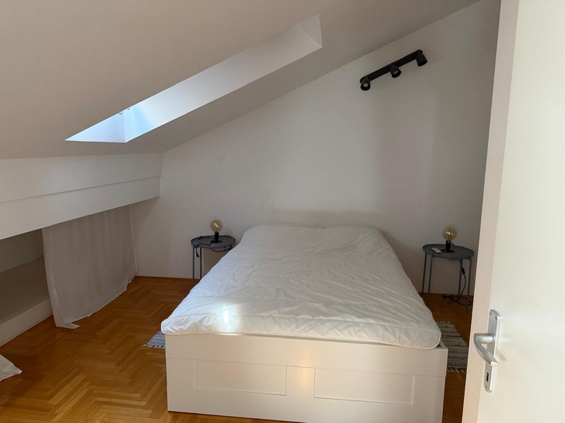 Podkrovní ložnice s postelí a střešním oknem