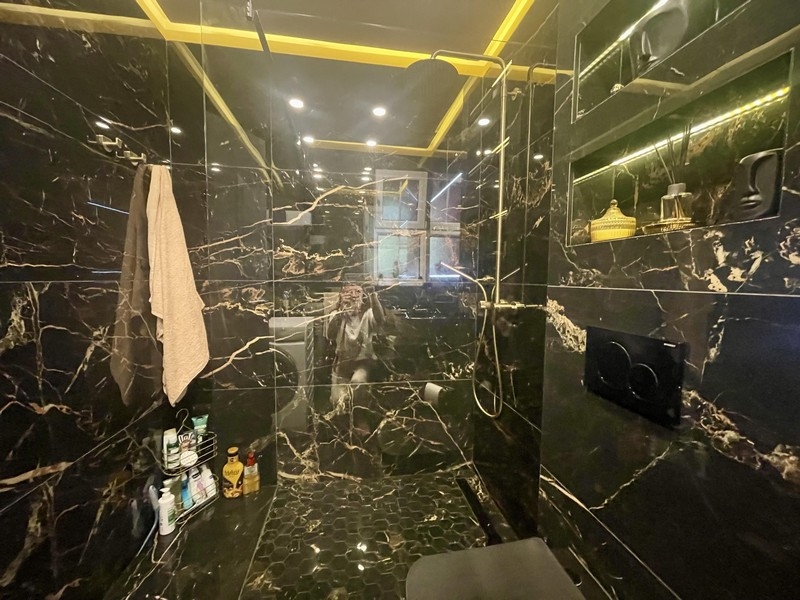 Koupelna s velkým sprchovým koutem a černým mramorovým designem