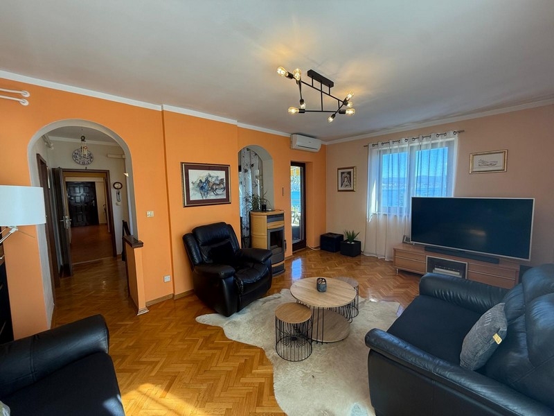 Obývací pokoj s černou koženou pohovkou a TV