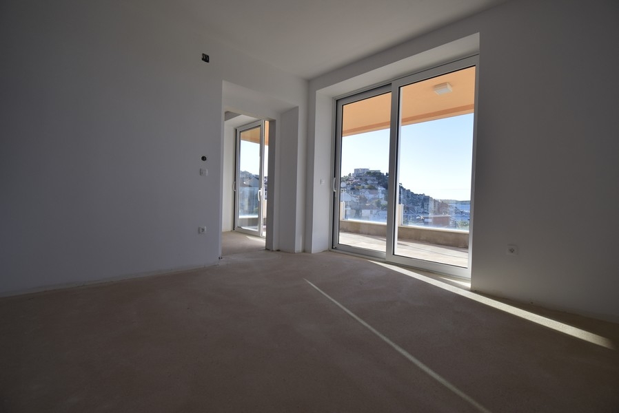 Světlý pokoj s velkými okny a vstupem na balkon