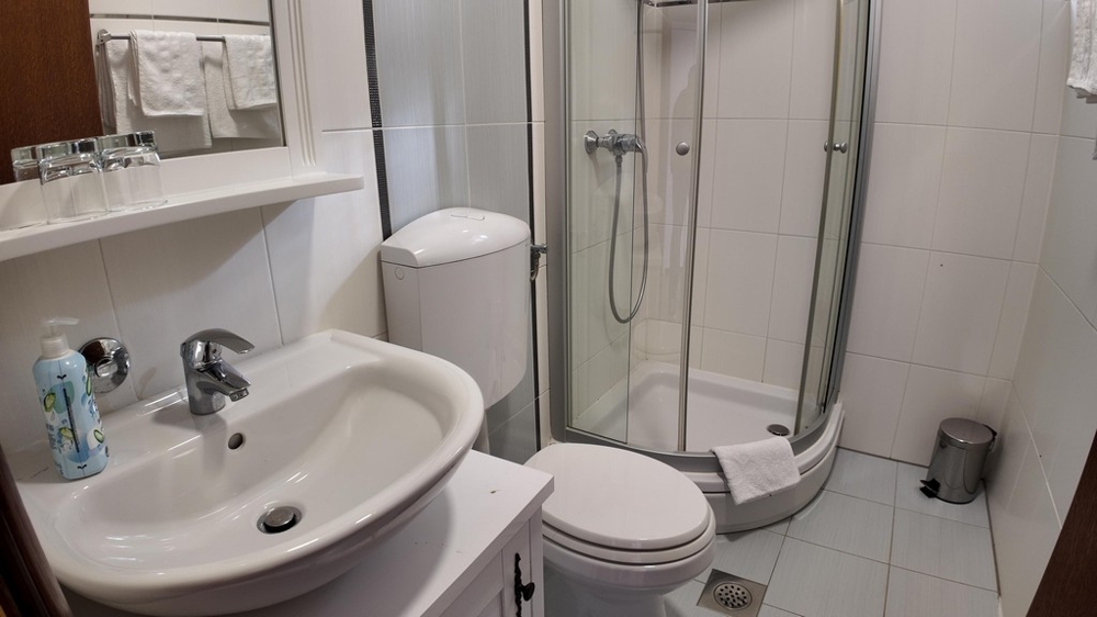 Koupelna se sprchovým koutem a umyvadlem - světlá dlažba