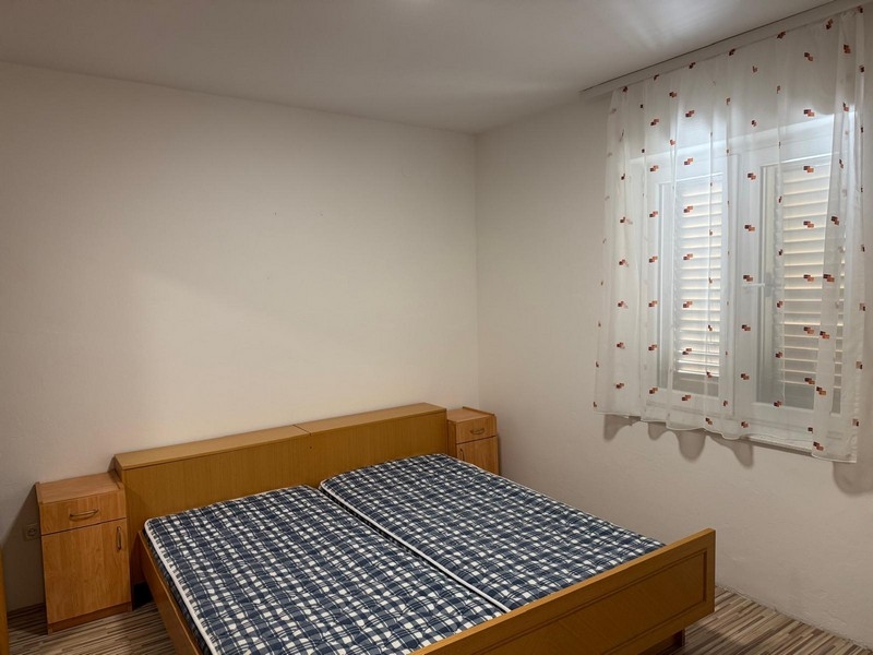 Světlá ložnice s manželskou postelí a okenicemi