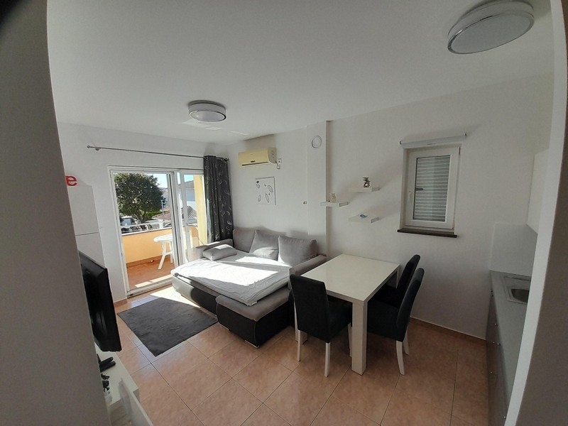 Obývací pokoj s pohovkou, jídelním stolem a vstupem na balkon s výhledem na moře