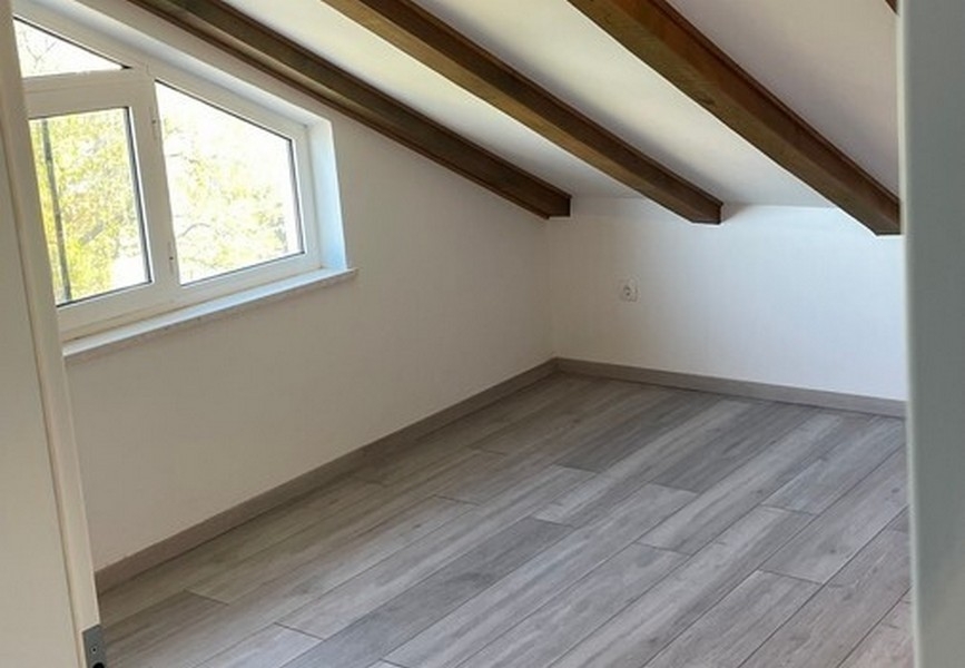 Podkrovní pokoj s odhalenými střešními trámy