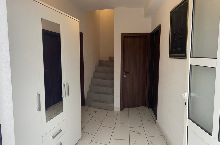 Vstupní prostor se schodištěm a bílým vestavěným nábytkem