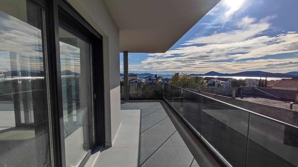 Balkon nového bytu se skleněným zábradlím a výhledem na moře