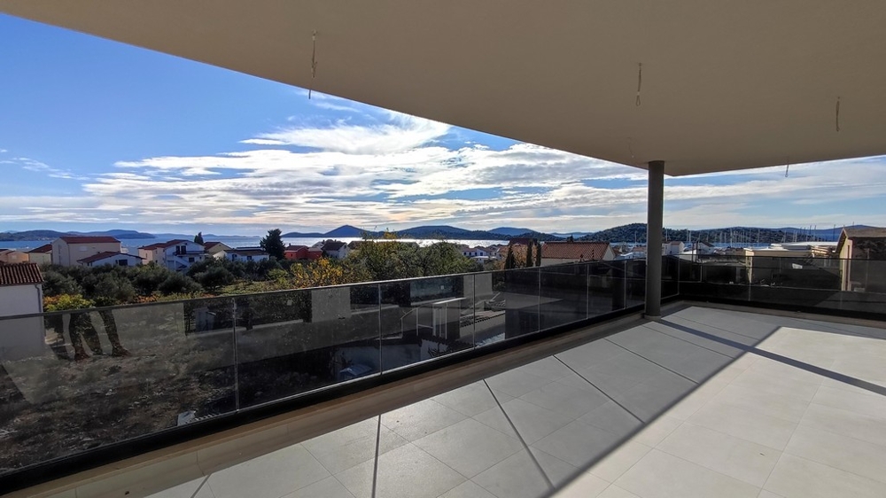 Velká krytá terasa s výhledem na střechy a moře