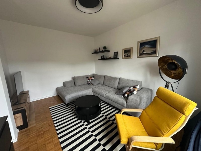 Obývací pokoj s šedou rohovou pohovkou a žlutým křeslem
