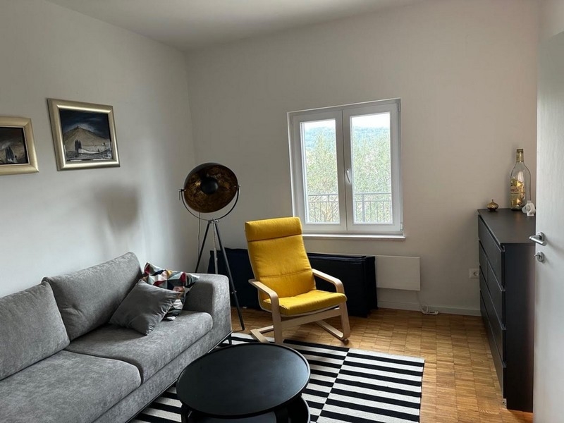 Obývací pokoj s oknem a moderním křeslem