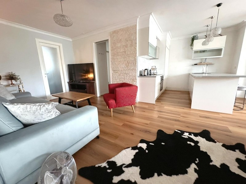 Obývací pokoj s pohovkou, červeným křeslem a otevřenou kuchyní